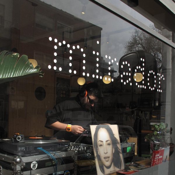 La vidriera con mirador escrito en puntos de luz y la bandeja de vinilos atrás
