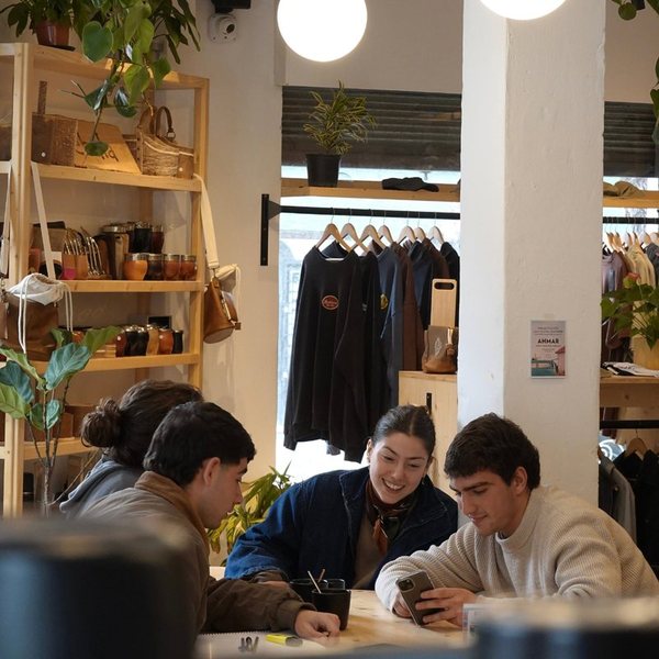 Cuatro amigos charlando y riendo en la mesa grande, con la tienda atrás